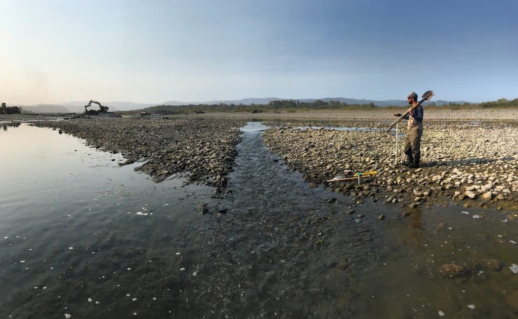 A worker surveys a human-made alteration in the gravel bar of the river for fish passage.